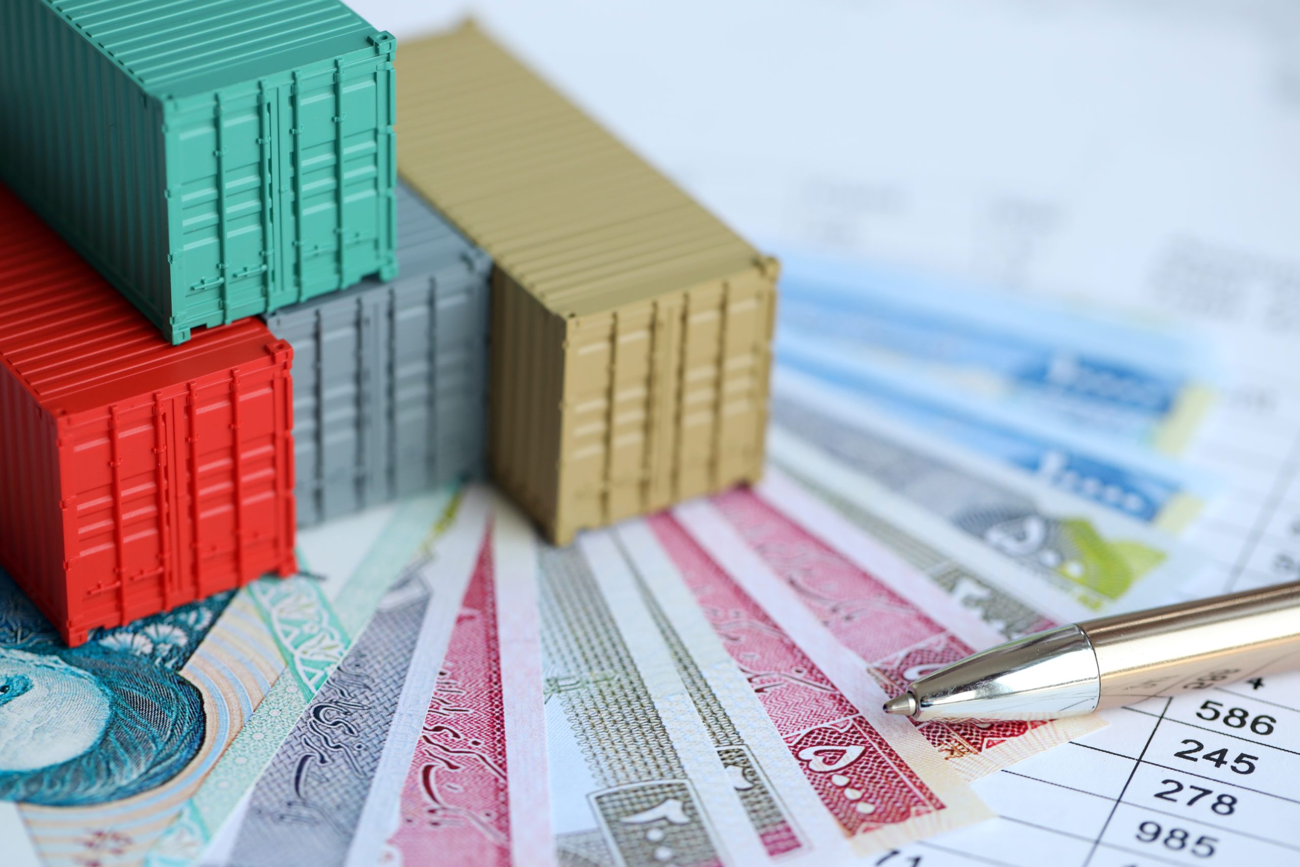 Company shipping cargo containers in Iran with rials money bills and pen